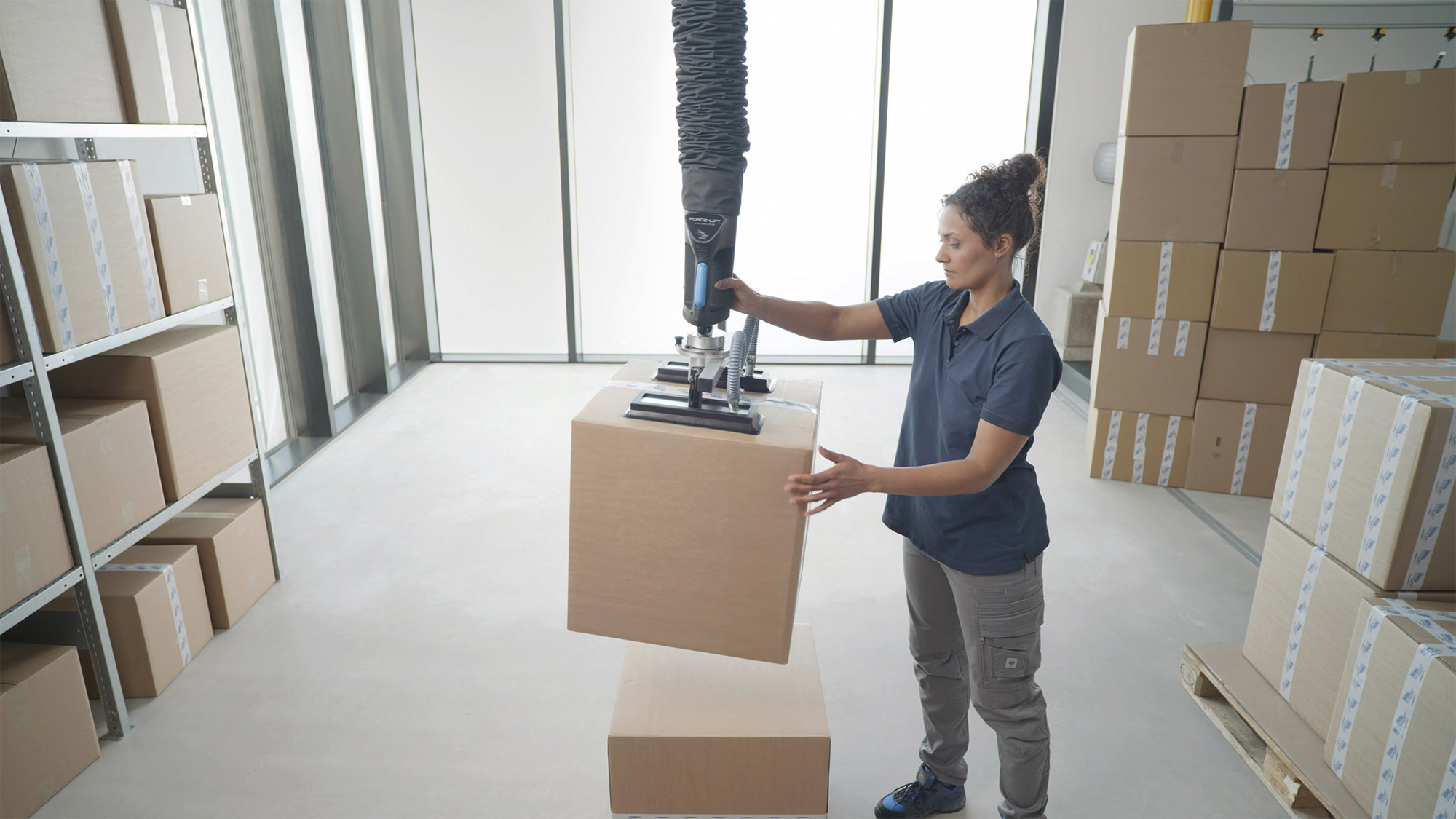 Aero-Lift gebruikt en ontwikkelt ultramoderne vacuümheftechnologieën. Foto van een werknemer van Aero-Lift die een kartonnen doos optilt met behulp van een buizenheffer